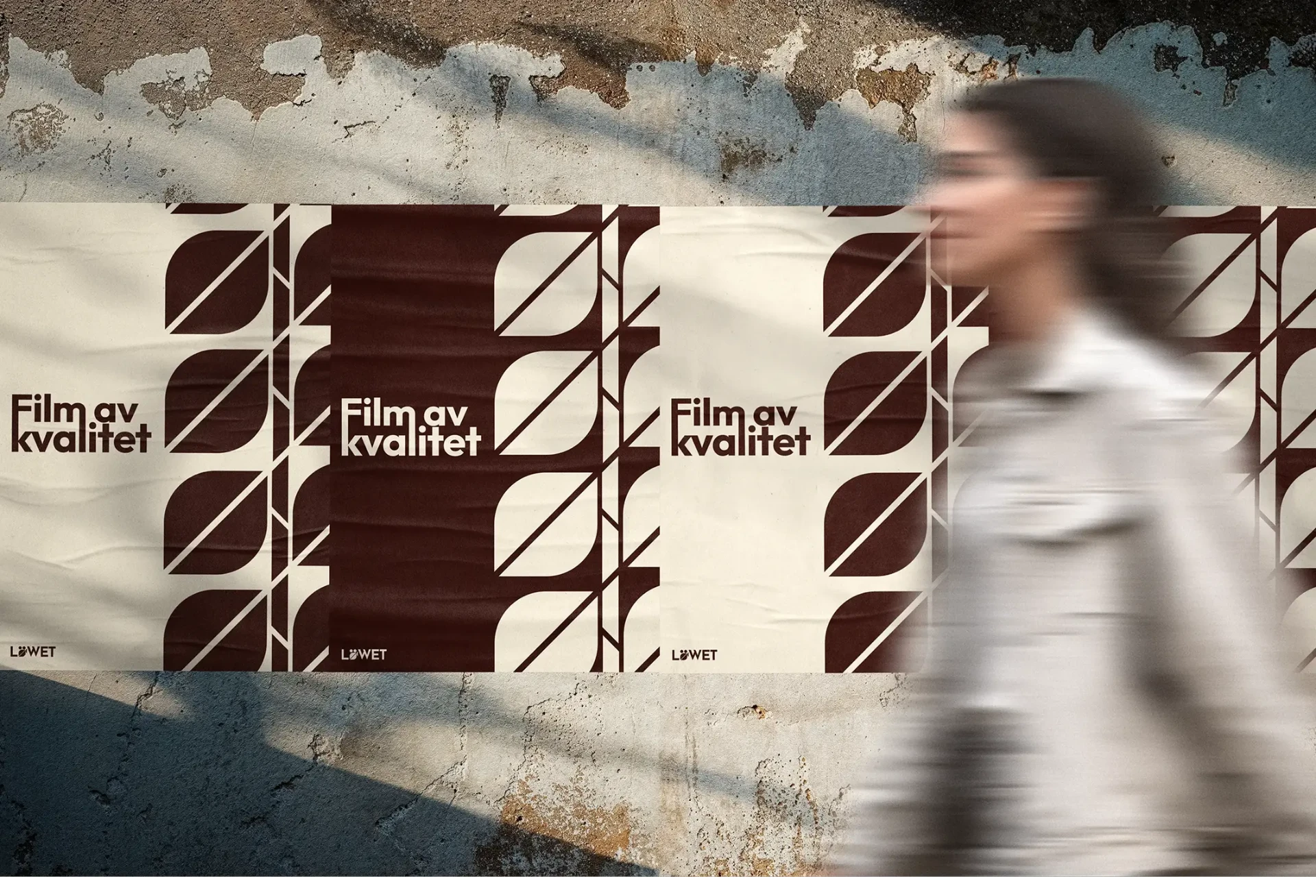 Löwet-affischer “Film av kvalitet” på en vägg med en förbigående person